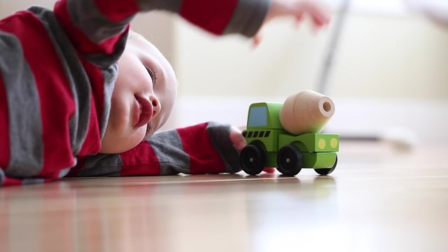a little boy plays with his toy wood truck