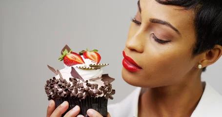 Fotobehang Zwarte vrouw die een fancy dessertcupcake met chocolade en aardbeien bewondert © rocketclips