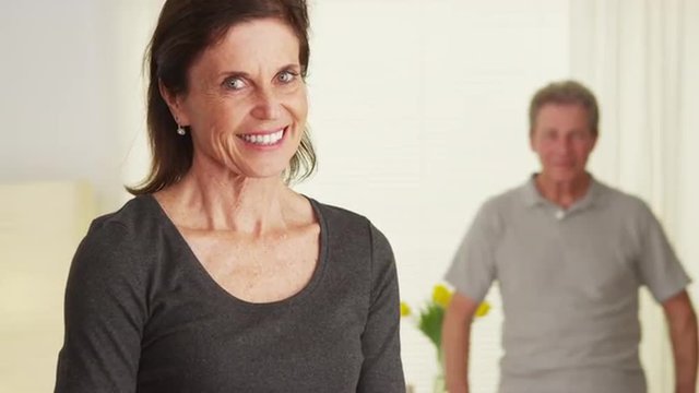 Elderly couple standing in living room smiling