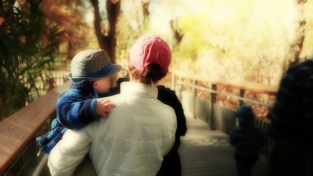 a mother and baby walking through zoo