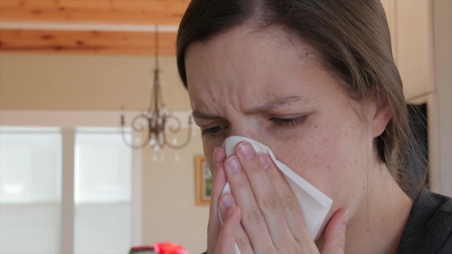Sick woman blows nose in kleenex
