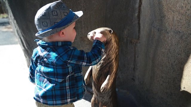 little boy and otter statue at the zoo