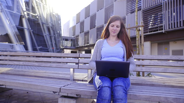 Casual businesswoman working on laptop outside 4K