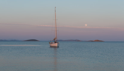 Fototapeta premium Sailboat in a Calm Bay under the Full Moon