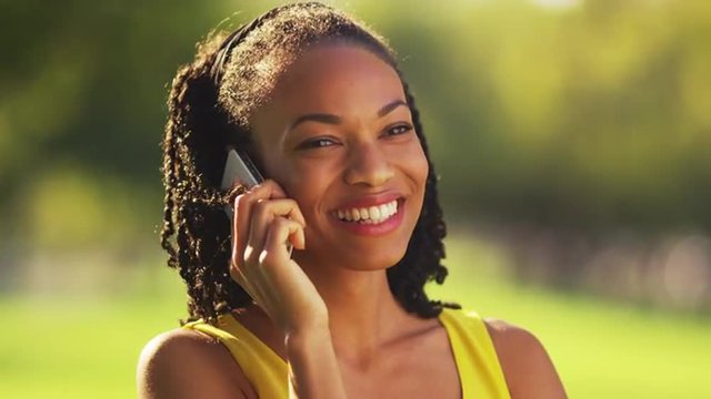 Black woman on the phone laughing outdoors