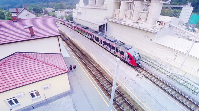 Electric train leaving station aerial flight over with panning