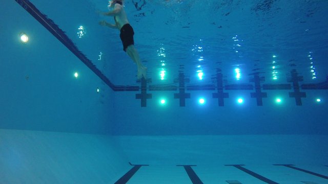 Underwater shot of man exiting deep swimming pool