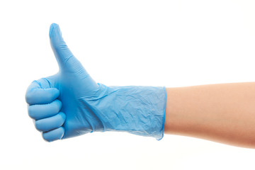 Doctor's hand in blue surgical glove showing thumbs up sign