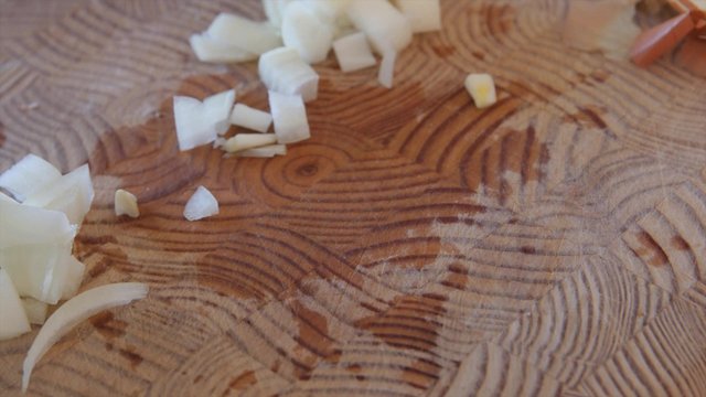 Woman dices an onion on a cutting board