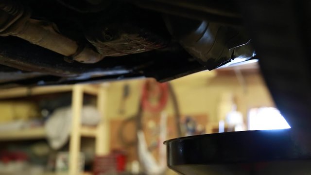 auto mechanic changing oil in a car