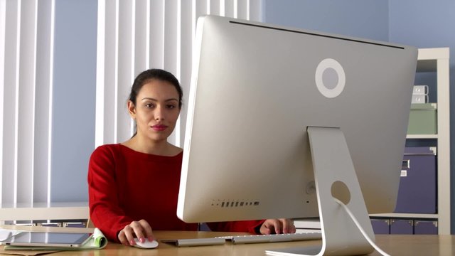 Mexican businesswoman happily working on computer