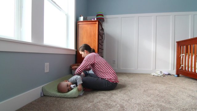 a mother wrestling to change her babies clothes