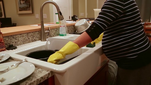 a pregnant woman washing dishes at the kitchen