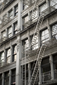 Traditional downtown New York City architecture featuring gray industrial facade lined with metal fire escapes
