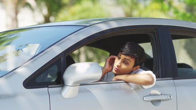 Black woman in car looking around and checking hair in mirror