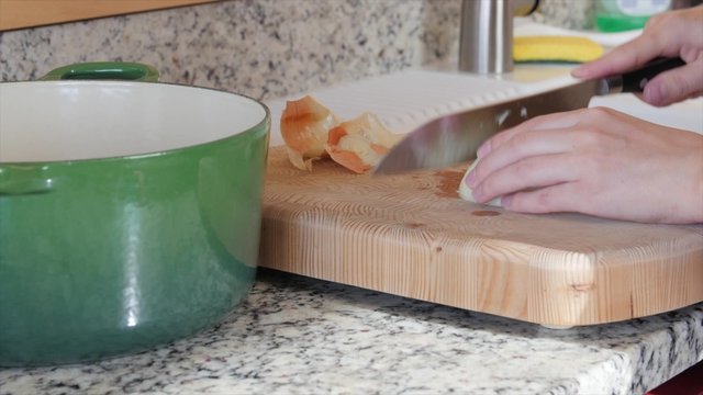 A mom dices an onion on a cutting board