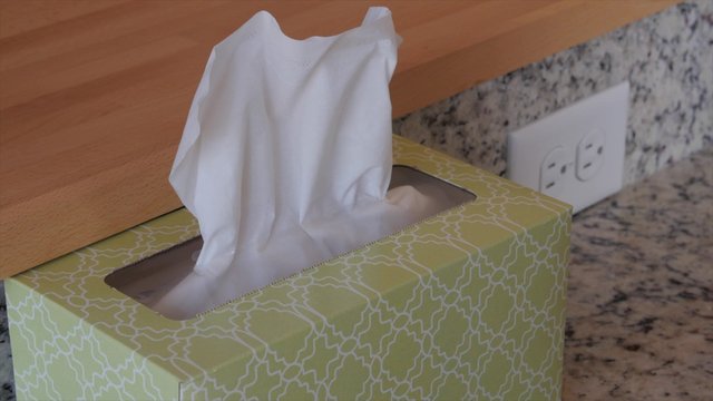 A hand grabs a kleenex tissue