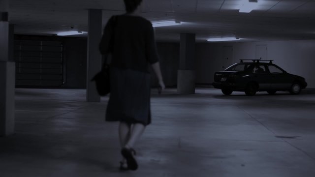 Woman walks to car in empty parking garage