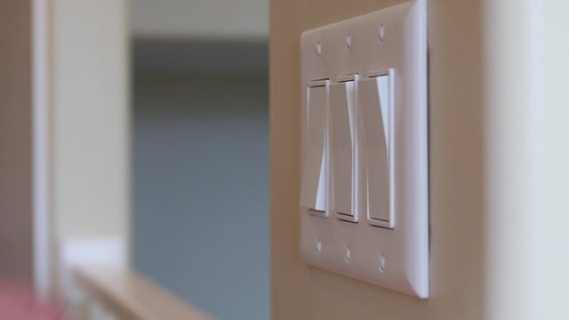 A man turns a light switch on and off