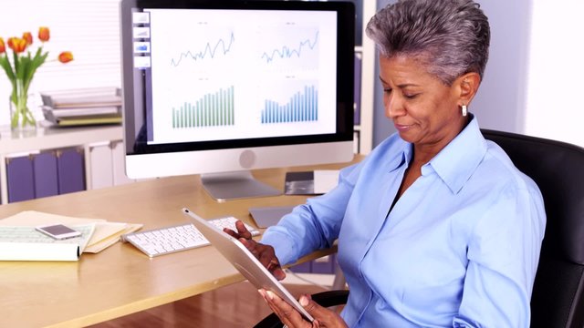 Senior african manager working at desk with tablet