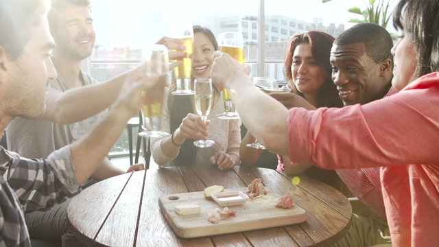 Group Of Friends Enjoying Drink And Snack In Rooftop Bar