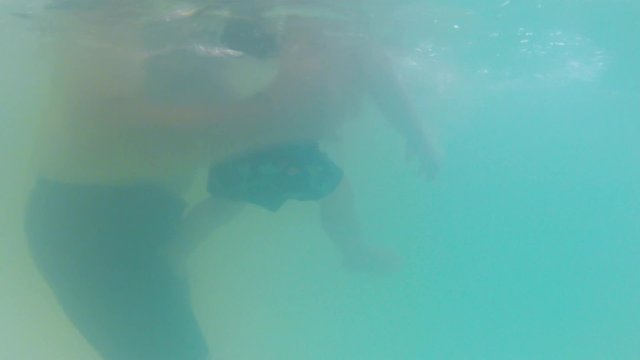 baby boy and mother swimming underwater shot