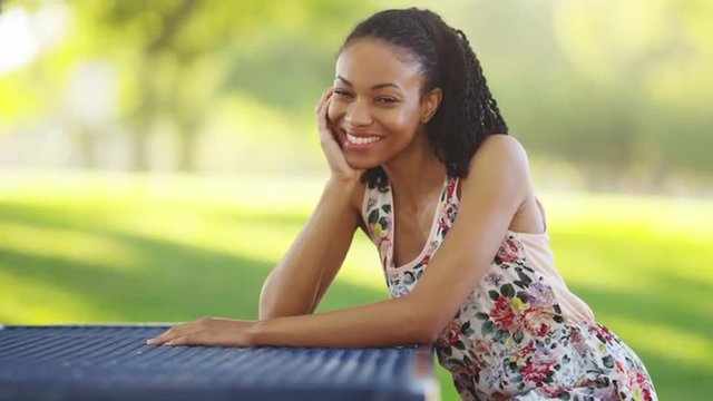 Black woman sitting on a park bench smiling