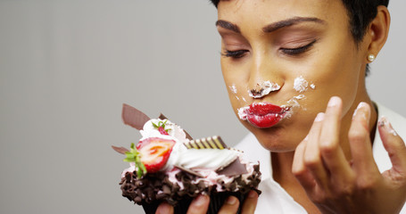 Black woman making a mess eating a huge fancy dessert - Powered by Adobe