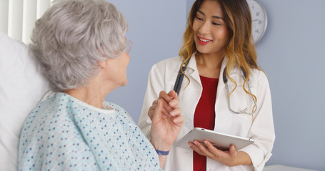 Asian doctor holding hand of elderly woman patient in hospital