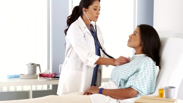 Hispanic female doctor listening to patient with stethoscope