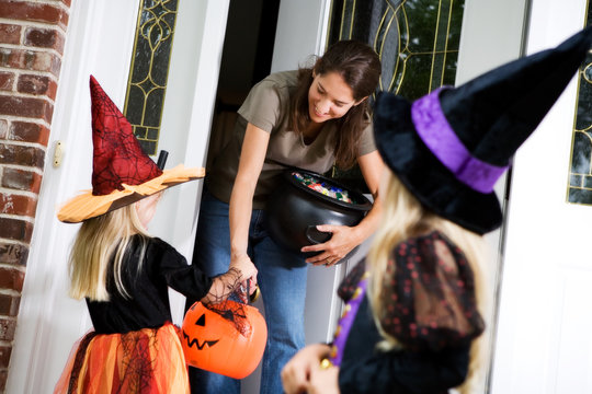 Halloween: Mother Hands Out Candy to Little Girl Witch