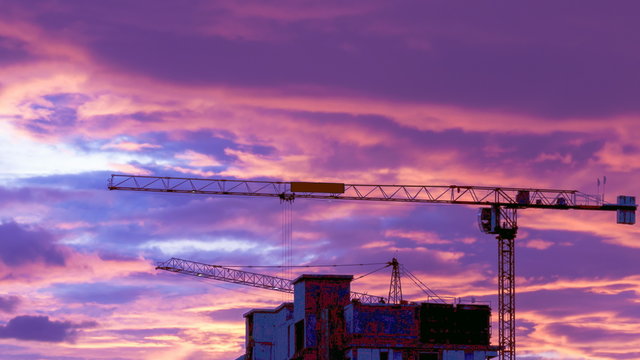 Silhouette Crane Working In Construction Site And Twilight Sky (pan shot)