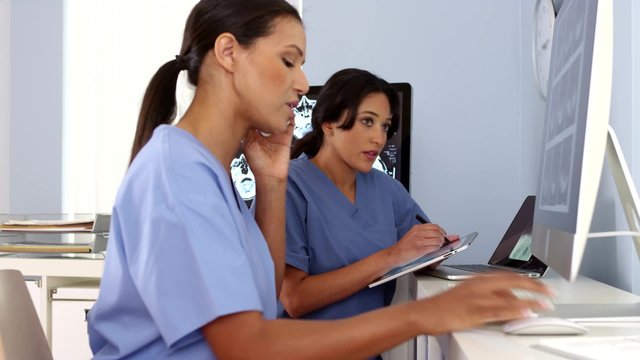 African American and Hispanic doctors working together on computers and phone