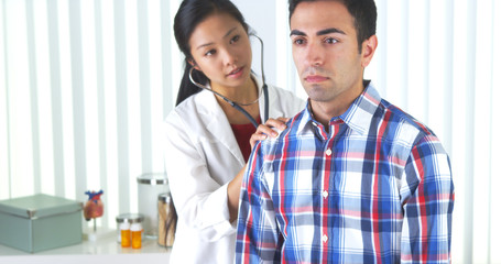 Fototapeta premium Chinese doctor listening to patient's lungs