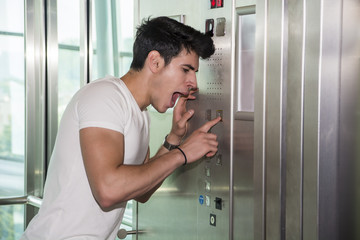 Naklejka na ściany i meble Scared young man desperate in stuck elevator