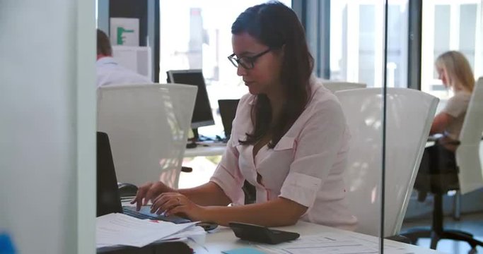 Businesswoman Working At Desk In Modern Open Plan Office