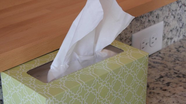 A hand grabing a kleenex tissue