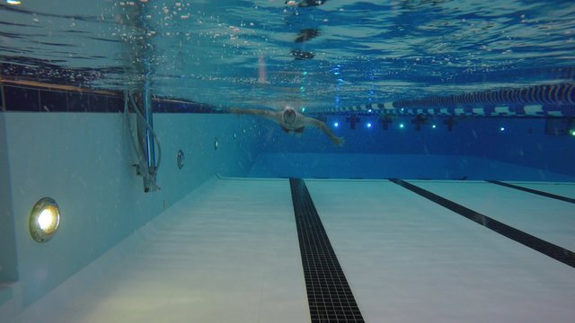 Underwater pool shot of a man walking toward camera