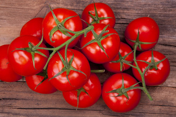 Bunch of tomatoes on vine shot cropped from above on a wooden background