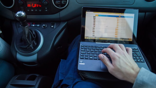 Person working on computer while driving in car