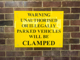 Parking warning sign on red brick wall