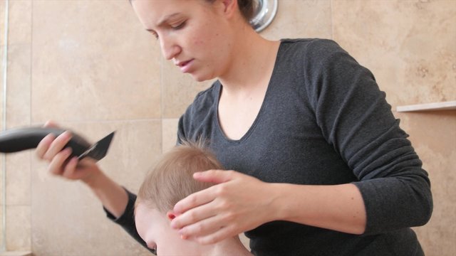 A mom cuts her little childs hair