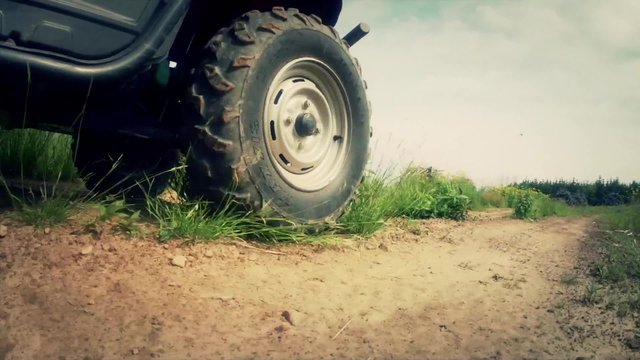 a low shot of a four wheeler traveling on dirt road