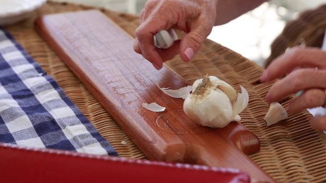 a lady peeling and preparing fresh garlic to make italian bruschetta