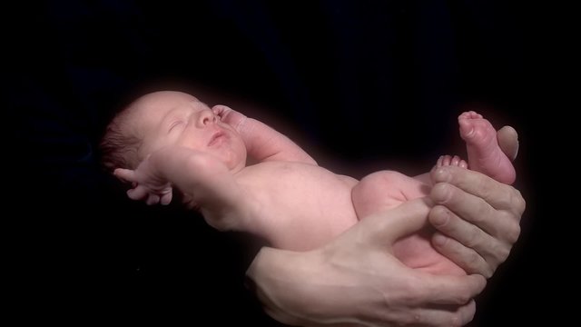 Hands Holding Newborn Baby on Black Background