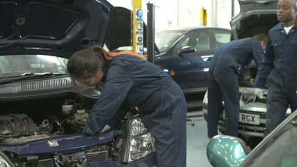 Teacher Helping Female Student Training To Be Car Mechanic