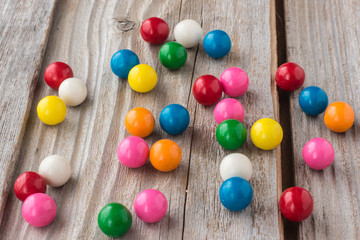 horizontal image of different coloured bubble gum scattered on an old rustic wooden background