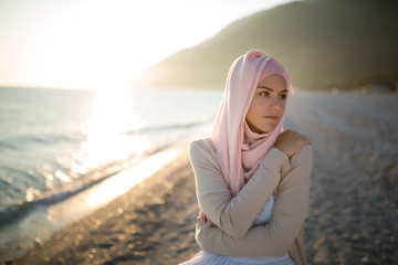 Muslim woman on the beach spiritual portrait.Humble muslim woman praying on the beach.Summer...