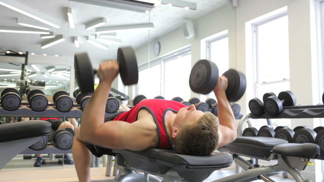 Young Man Working Out With Weights In Gym