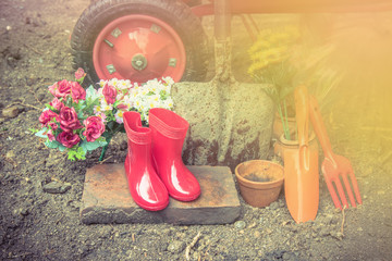 gardening tool including by red boots vase , fork , shovel and b